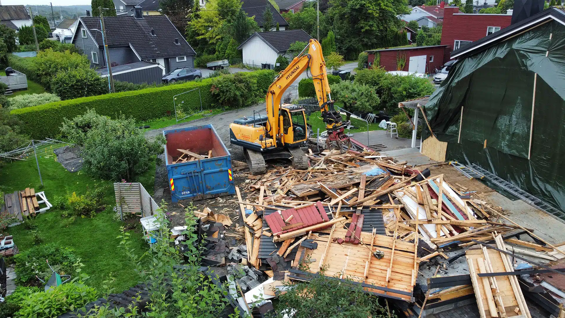 Gravemaskin som jobber med ett rivd hus.